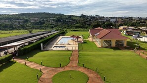 Un hotel con piscina, terraza techada y vistas del paisaje circundante.
