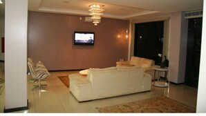 Una sala moderna con un sofá grande, un televisor montado en la pared y una araña.