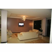 Uma sala de estar moderna com um sof á grande, uma televisão na parede e um candelabro.