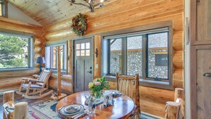 Ein Holzblockhaus-Interieur mit einem Holzesstisch, Stühlen und einer Chandelüster.