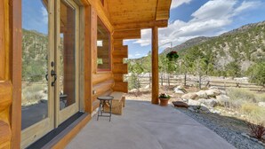 Eine Holzhütte mit großen Glasüren, einer Beton-Terrasse und Blick auf eine Berglandschaft.