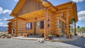Eine Blockhütte mit großer Veranda, Stein Fundament und Blumentöpfen.