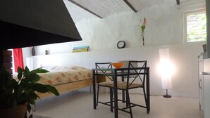 A room with a bed, a table with chairs, a potted plant, a lamp, and a window. - Cottage with private terrace and view of the park! (Apt)
