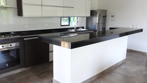 A modern kitchen with white cabinets, stainless steel appliances, and a black countertop. - Finca Hotel San Jose (Montenegro)