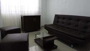 A modern living room with a dark leather sofa, a glass coffee table, and a dark wooden cabinet. - Finca Hotel San Jose (Montenegro)