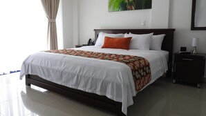 A hotel room with a large bed, a bedside table with a lamp, a phone, and a wall-mounted painting. - Finca Hotel San Jose (Montenegro)