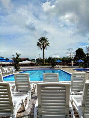 A pool area with white lounge chairs and a palm tree. - Finca Hotel San Jose (Montenegro)