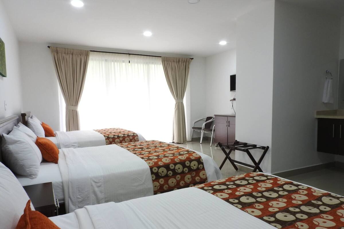 A hotel room with two beds, a desk, and a chair.
