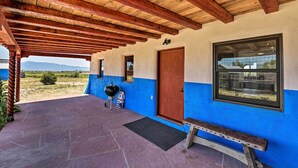 Ein überdachter Balkon mit Holzboden, einer blau-weißen Außenwand, einer Holztür und einem Fenster.