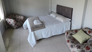 Een slaapkamer met een bed, een nachtkastje, een stoel en een airconditioning.