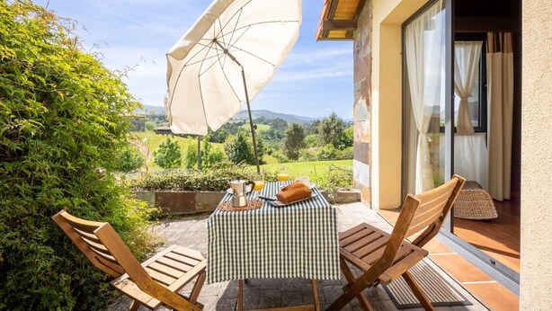 Eine Terrasse im Freien mit Tisch, Stühlen und einem großen Sonnenschirm.