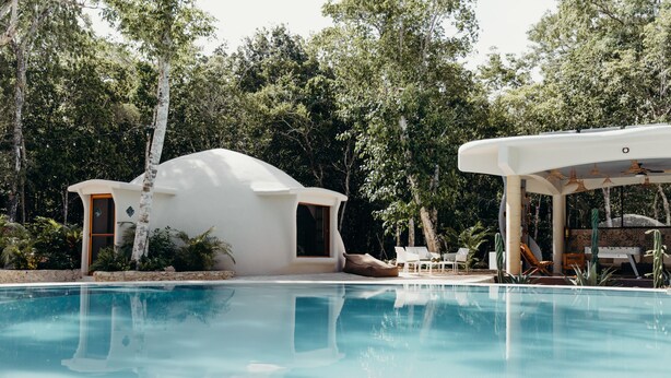 A modern pool area with a white dome-shaped structure and a covered seating area.