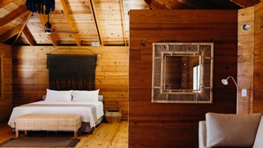 A wooden cabin bedroom with a bed, bench, and a mirror on the wall.