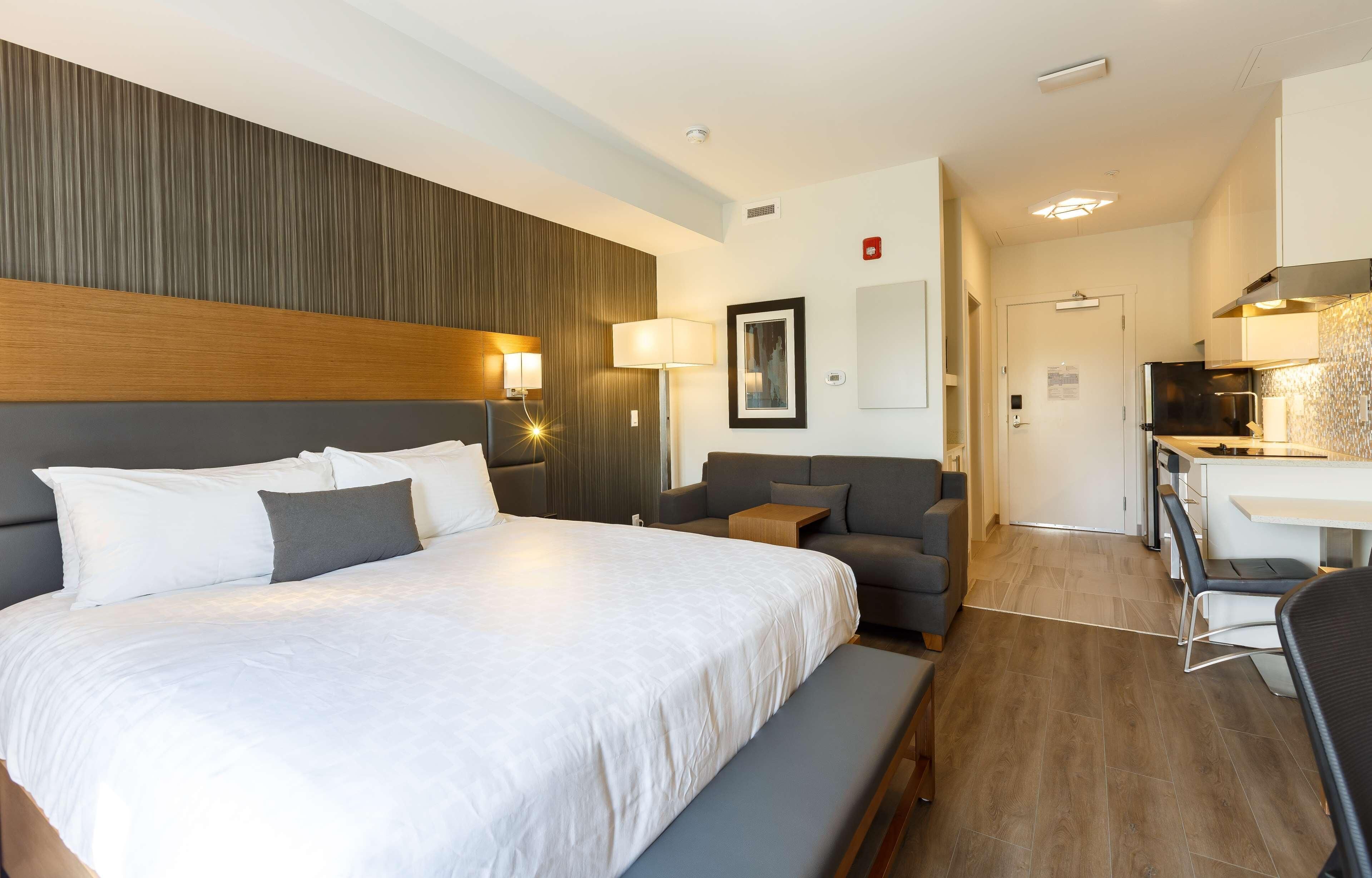 Una habitación de hotel con una cama grande, un sofá, un escritorio y una kitchenette.