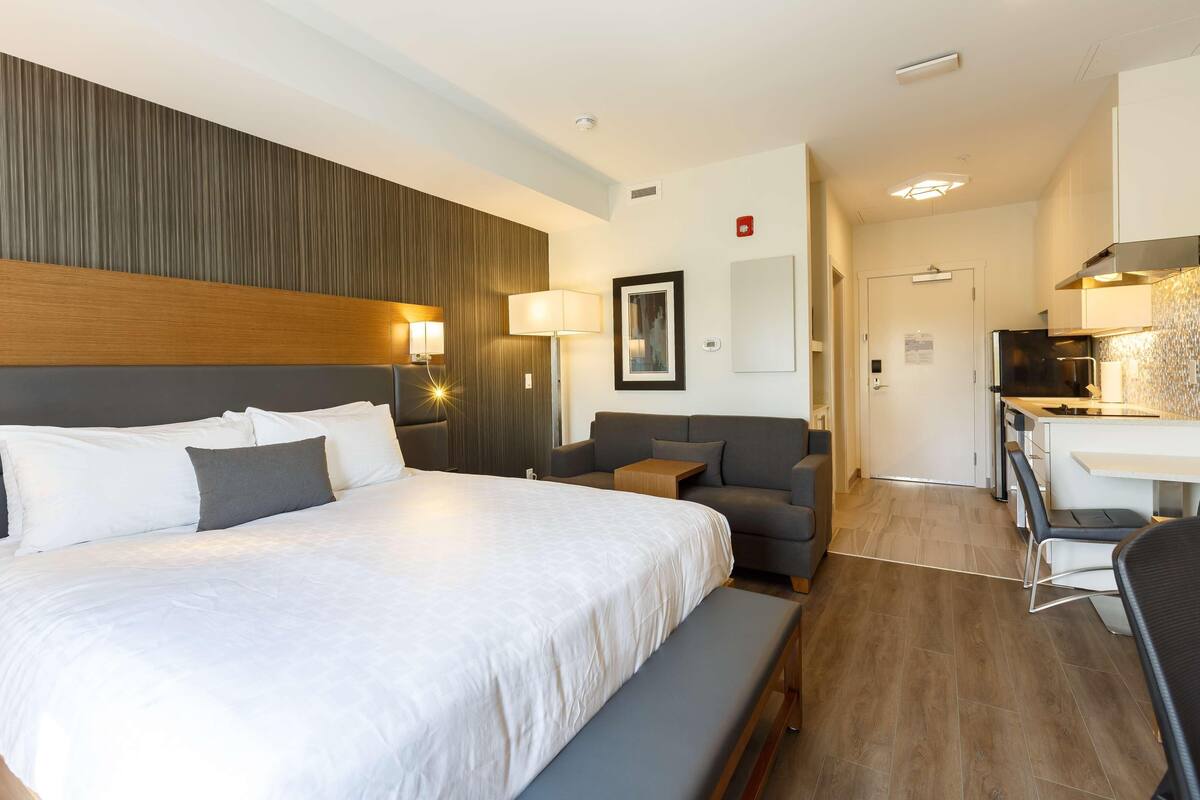 Una habitación de hotel con una cama grande, un sofá, un escritorio y una kitchenette.