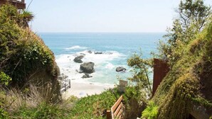 A coastal walkway with a wooden bench, leading to a beach with visible waves and rocks. - Oceanfront retreat w/ AC & beach access (Laguna Beach)