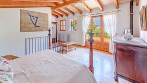 Un dormitorio con una cama, un aparador de madera, una escalera y un balcón con vistas.