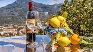 A table with a bottle of wine, two glasses, and a bowl of lemons.