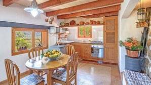 Una cocina con vigas de madera, una mesa de comedor con sillas, una estufa y una ventana con vistas al verdor.