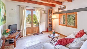 Una sala de estar con televisor, muebles de madera, una estantería y una ventana con vistas.