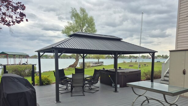 En overdækket terrasse med bord og stole, grill og boblebad.