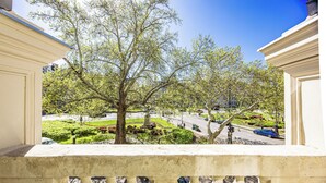 A balcony with a view of a park, a statue, and a street with cars. - Count Andrassy Luxurious Residence (VI. kerület)