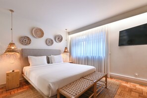 A modern hotel room with a large bed, bedside lamps, a flat-screen TV, and decorative wall plates. - Sleep in Office (Porto)
