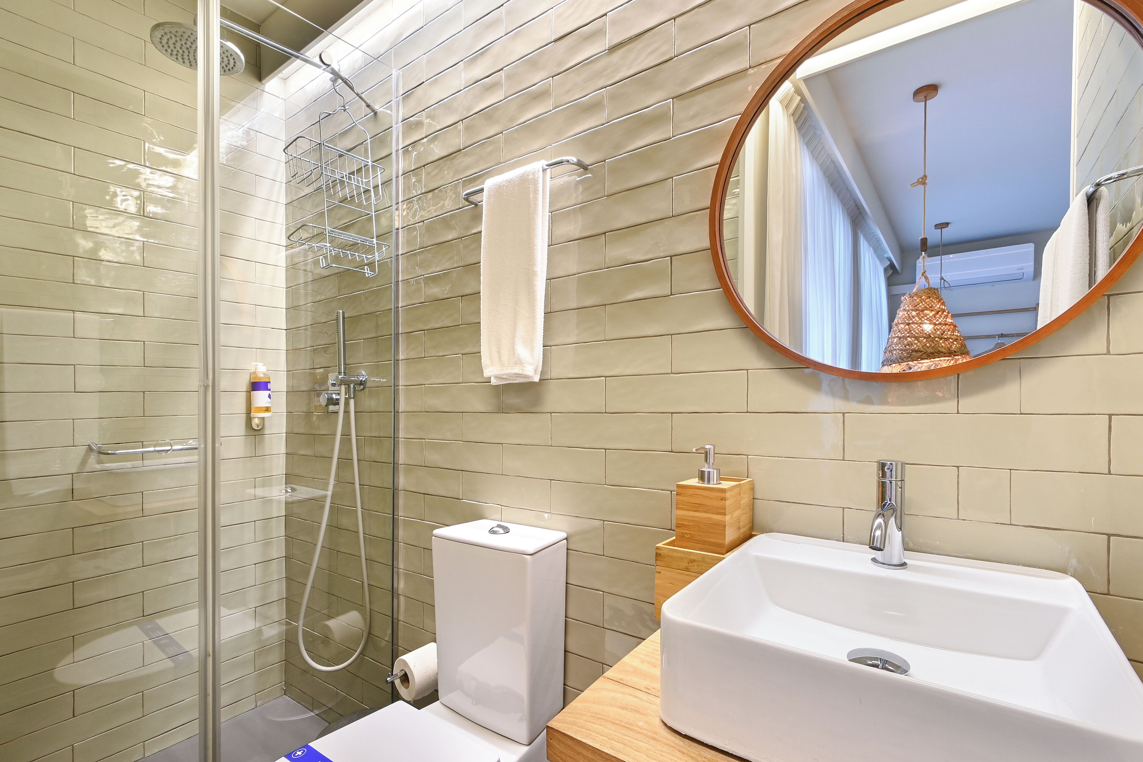 Een moderne badkamer met een douchecabine van glas, een toilet, een wastafel en een spiegel.