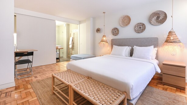 A modern bedroom with a large bed, bedside tables, a desk, and a bench. - Sleep in Office (Porto)