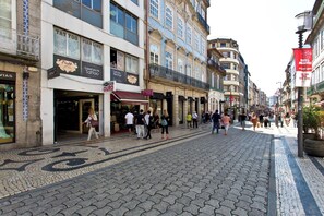A cobblestone street lined with shops, including a tattoo parlor and a clothing store. - Sleep in Office (Porto)