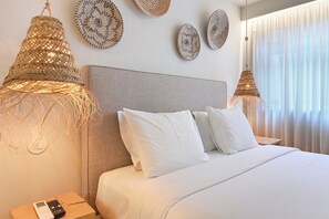 A hotel room with a bed, white bedding, a bedside table with a remote control, and woven lampshades. - Sleep in Office (Porto)