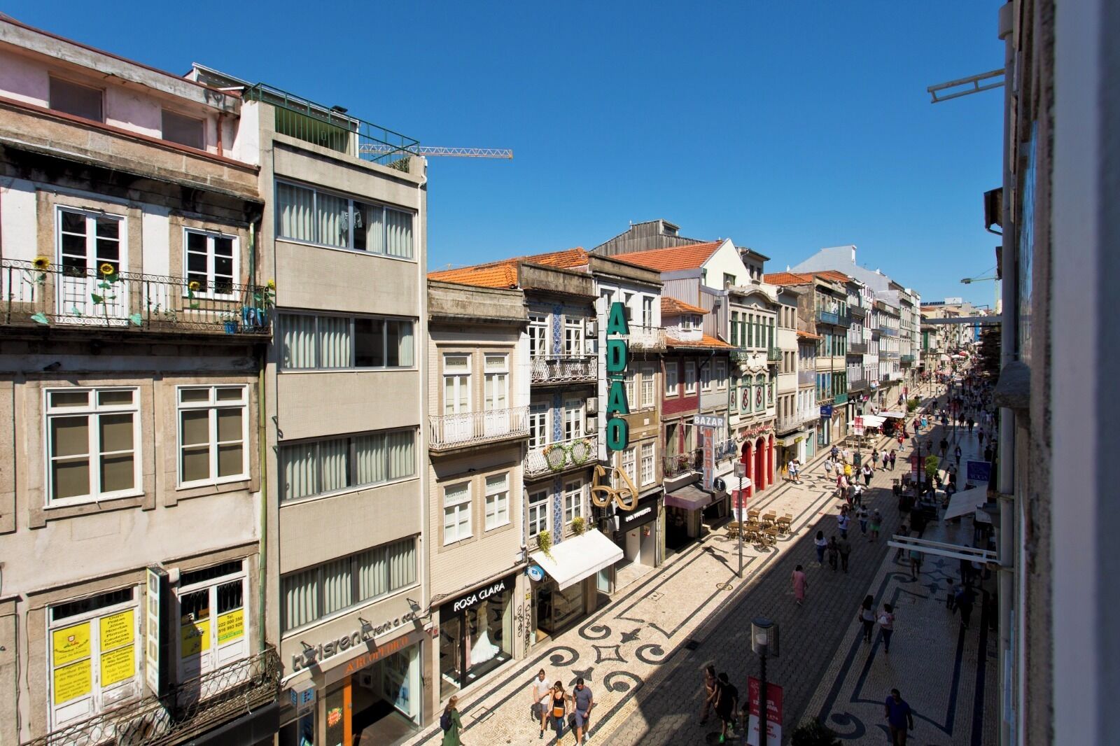 A street view with multi-story buildings, shops, and a pedestrian area.