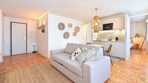 En moderne stue med sofa, spiseplads og køkken.