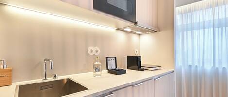 A modern kitchen with a stainless steel sink, a built-in oven, and a microwave above the counter.