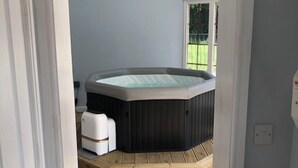Een kamer met een houten vloer, een bubbelbad en een raam.
