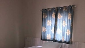 Un dormitorio con una cama grande, una mesita de noche y una ventana con cortinas florales.