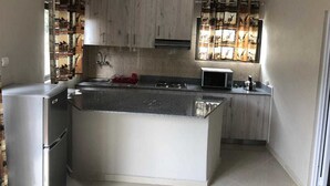 Una cocina compacta con una isla central, horno microondas integrado y refrigerador.