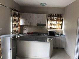 Una cocina compacta con una isla central, horno microondas integrado y refrigerador.