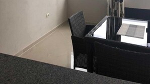 Una habitación con una mesa de comedor y sillas, un televisor montado y una ventana con cortinas.