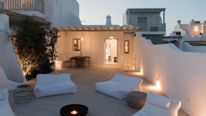 A rooftop terrace with white lounge chairs, a small table, and a candle. - Traditional Cycladic Home with a large private pool with sea view (Mikonos)