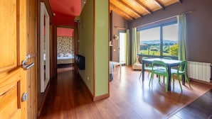 A spacious room with a wooden ceiling, a dining area with green chairs, and a view of the outdoors. - Apto. 3. La mar salada (Castiello De La Marina)