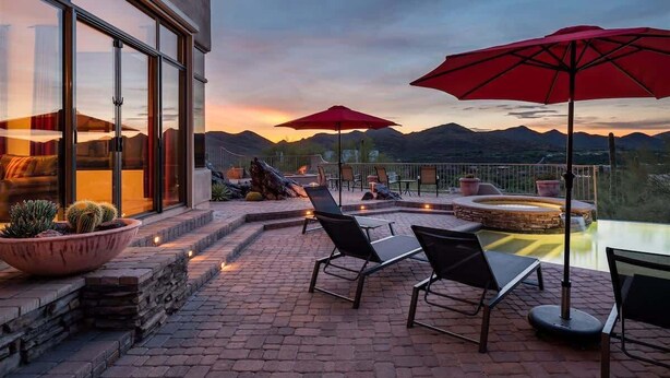 A patio with outdoor seating, a hot tub, and a view of mountains. - Southwest home w/ Hot Tub, heated* pool, and amazing Mtn. Views! (Cave Creek)