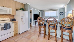 A kitchen with a stove, microwave, refrigerator, and wooden chairs. - Beach & Tennis 2005 (Bonita Springs)