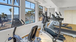 A gym with treadmills, an elliptical, and a pool view.