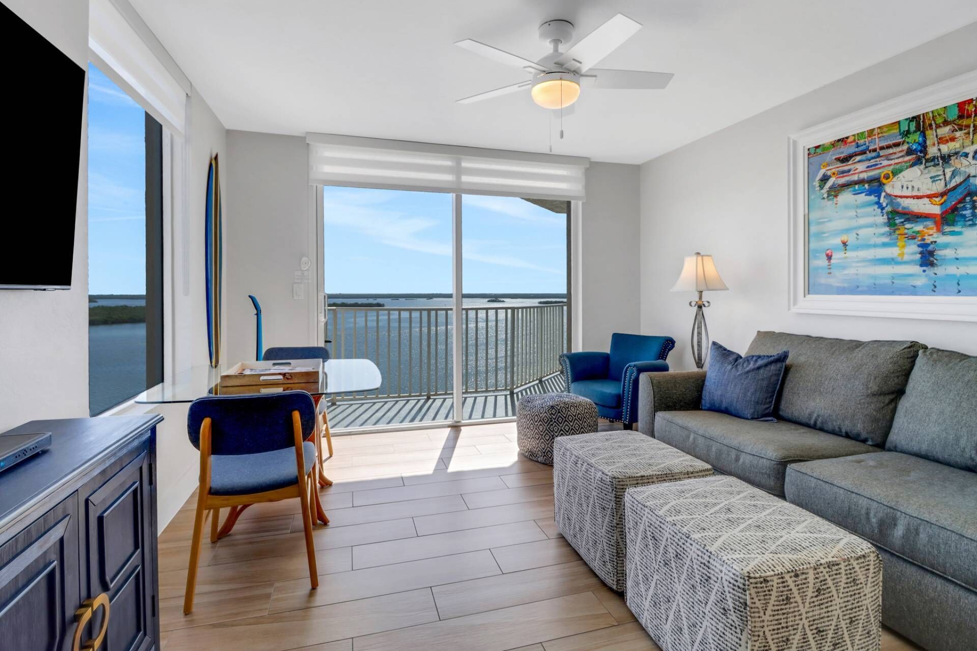 Een balkon met uitzicht op zee, een bank, een tafel met stoelen en een plafondventilator.