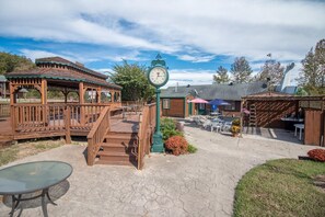 A wooden gazebo, a clock, outdoor seating, and a small garden area. - Bullwinkles Rustic Lodge (Poplar Bluff)