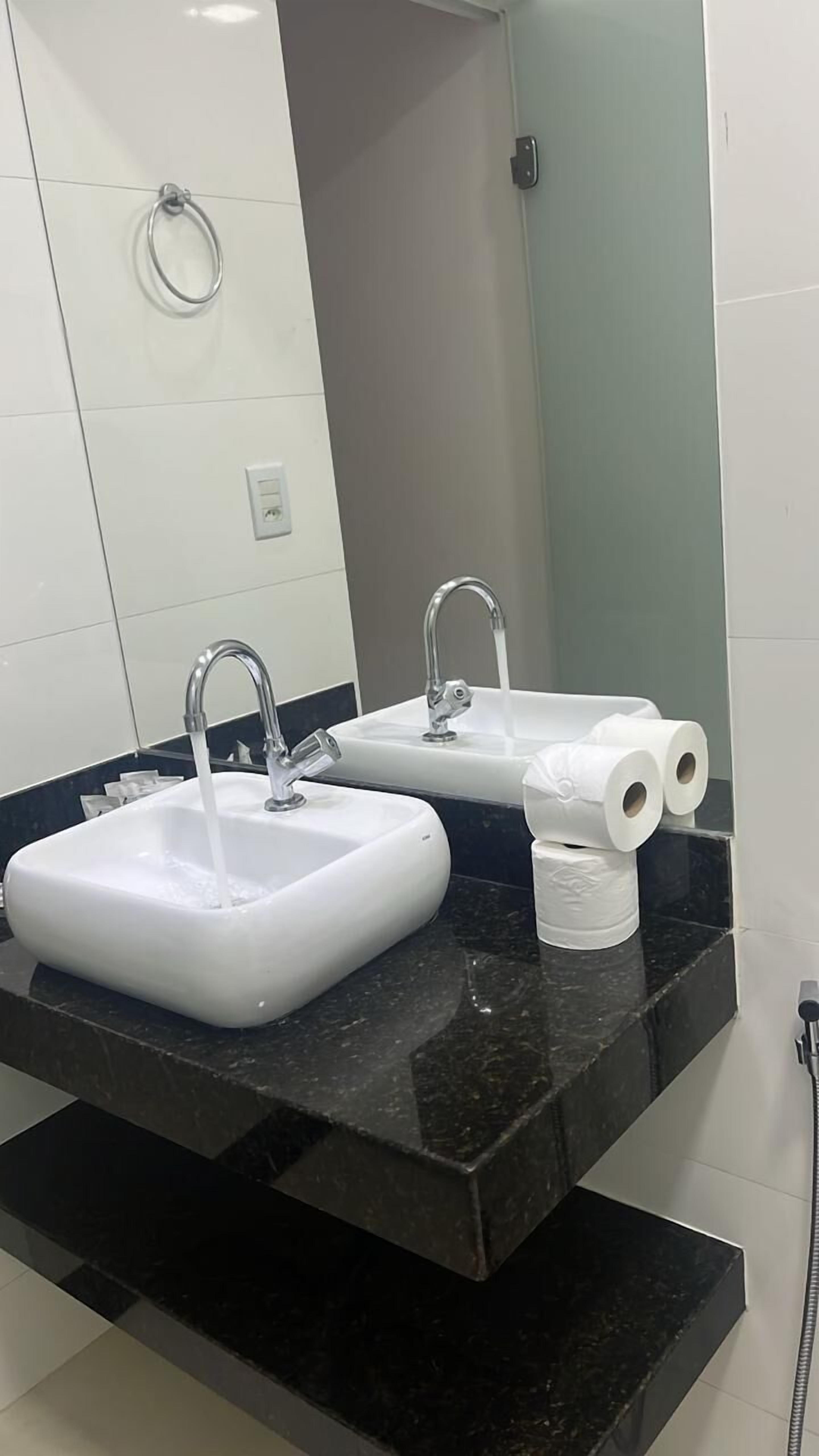 A bathroom with two sinks, a mirror, and a toilet paper holder.