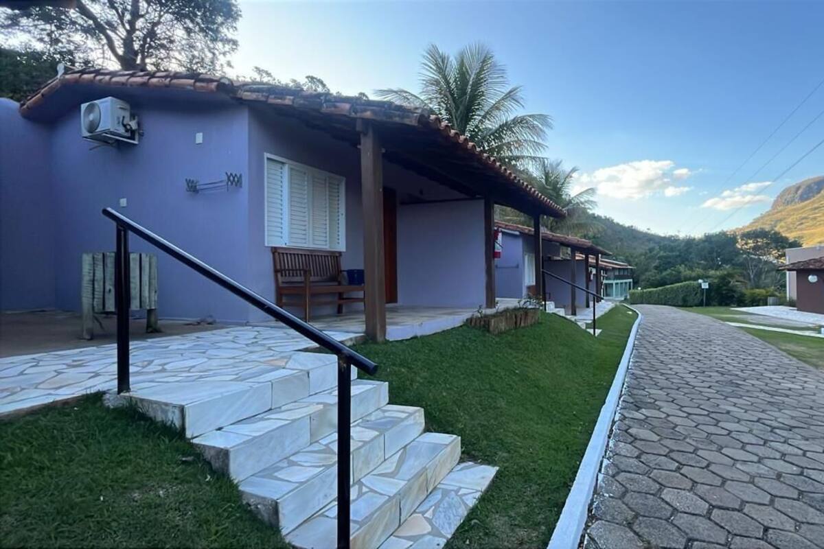 Un edificio de dos pisos con techo de tejas, un porche cubierto y una escalera de piedra que conduce a la entrada.