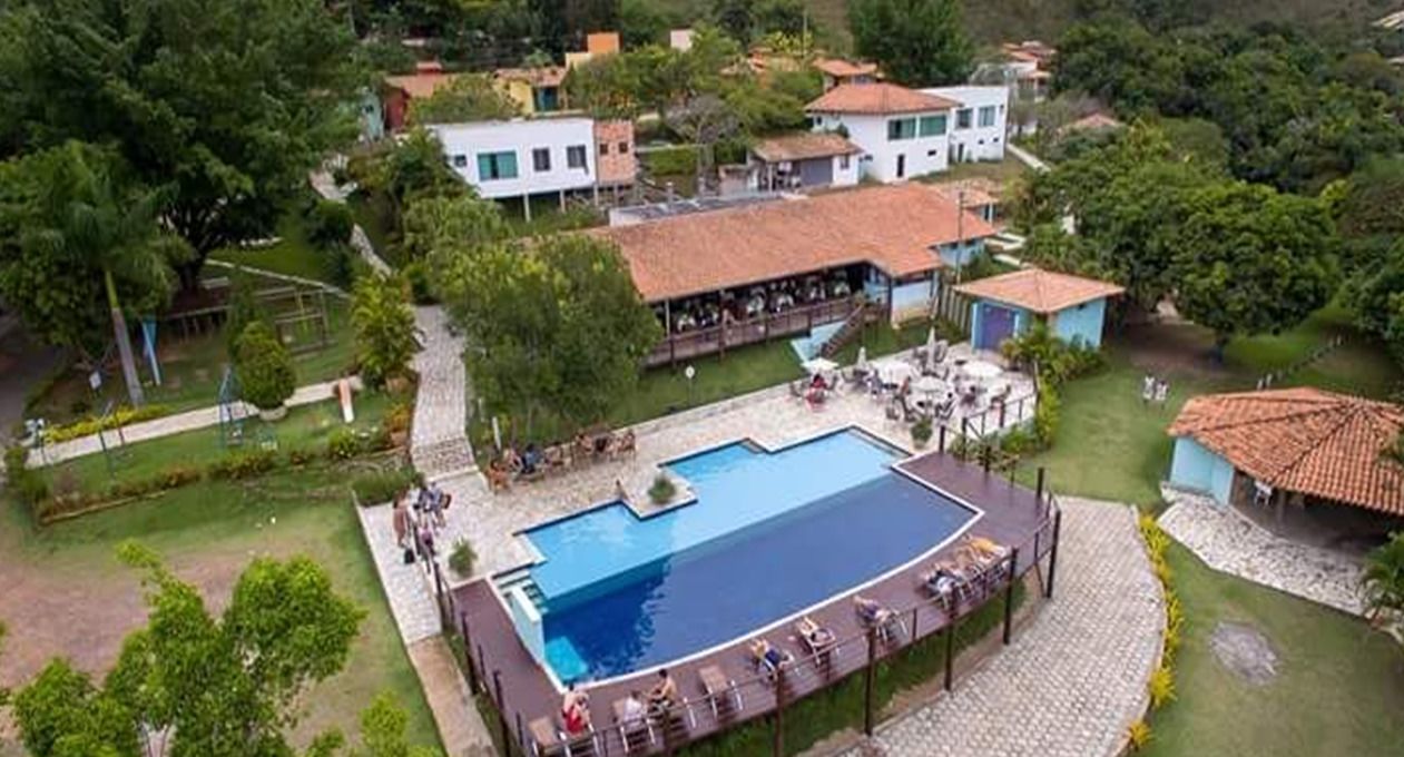 Eine Vogelperspektive eines Resorts mit einem großen Schwimmbad, umgeben von üppiger Vegetation und mehreren Gebäuden.