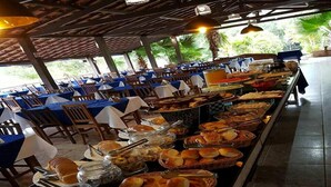 Montaje de bufé con diferentes alimentos y mesas dispuestas en un espacio cubierto.
